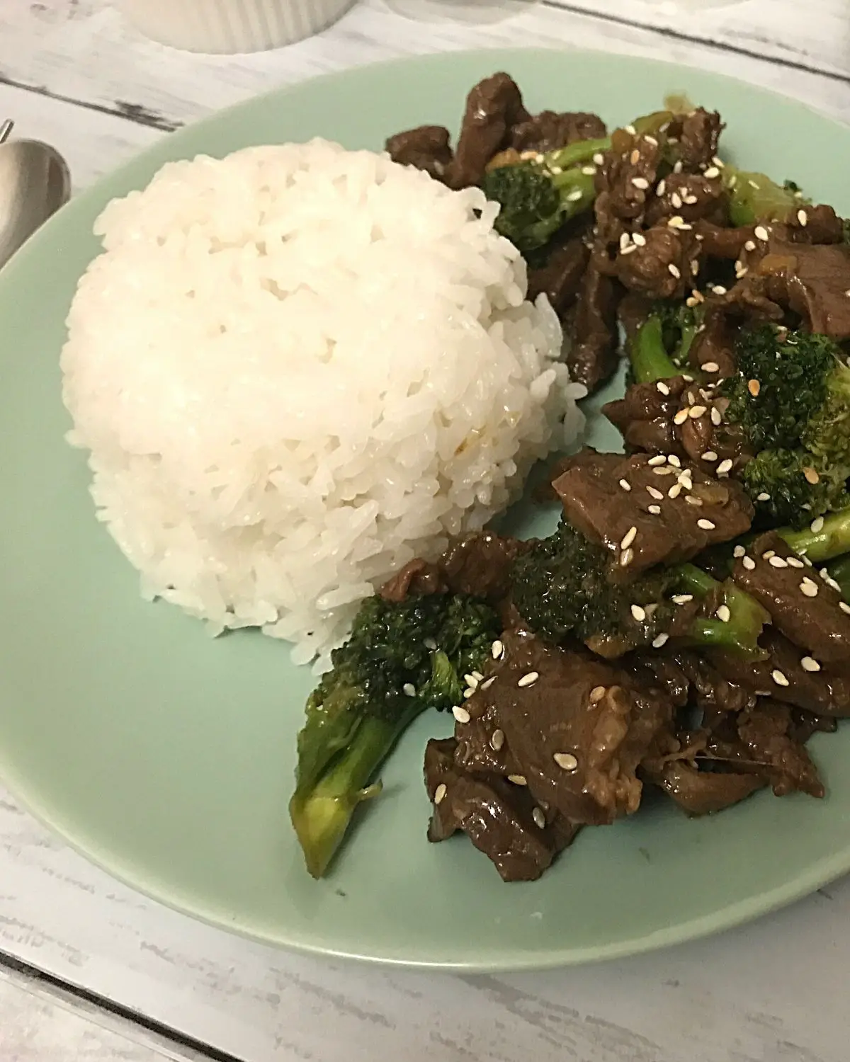 beef with broccoli served with rice in a green round plate